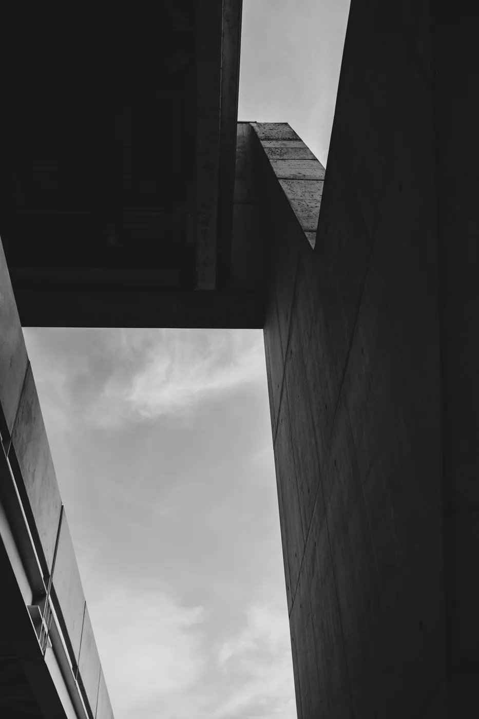 Angular concrete forms framing an opening onto a pale sky