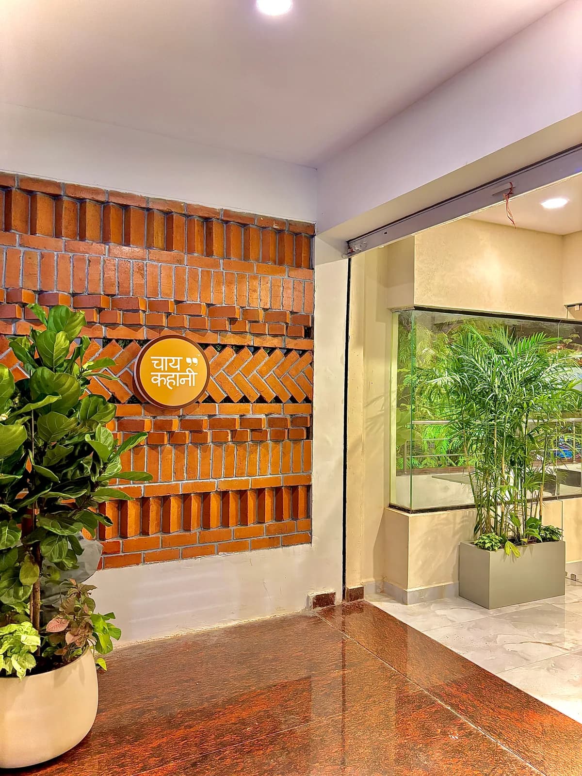 A terracotta lattice screen rising behind a planted bed and a lit brand plaque