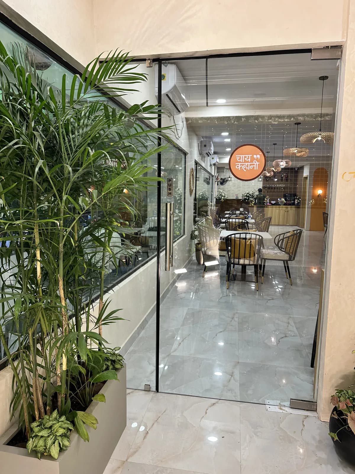 An entrance walk beside planting, the cafe visible through full-height glazing
