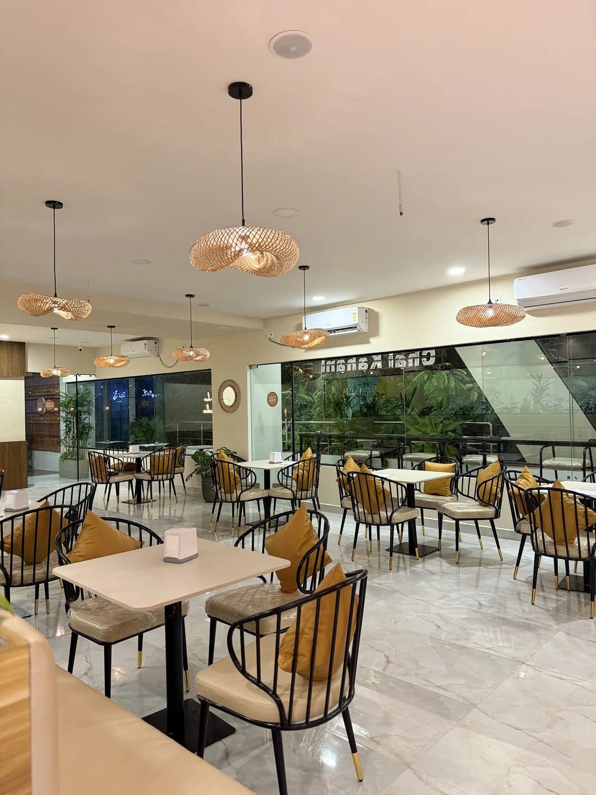The cafe floor set with tables under copper pendants