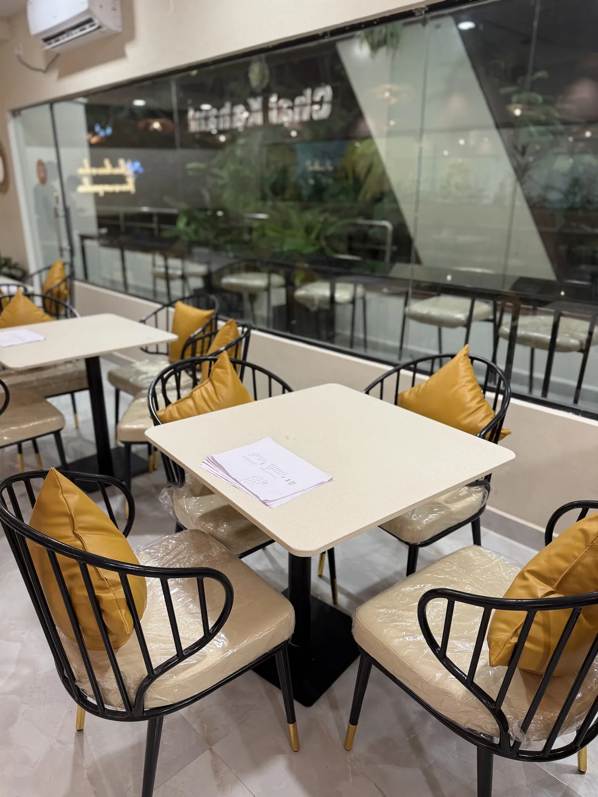 Window tables with mustard cushions looking onto the street