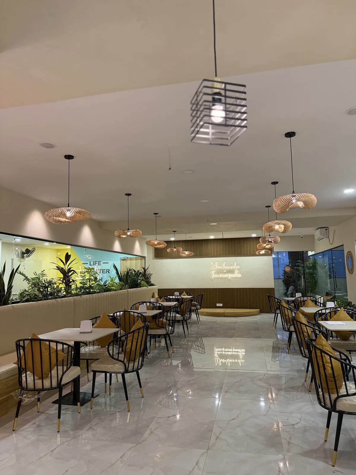 A cafe interior with a caged pendant above the tables and a lit rear wall