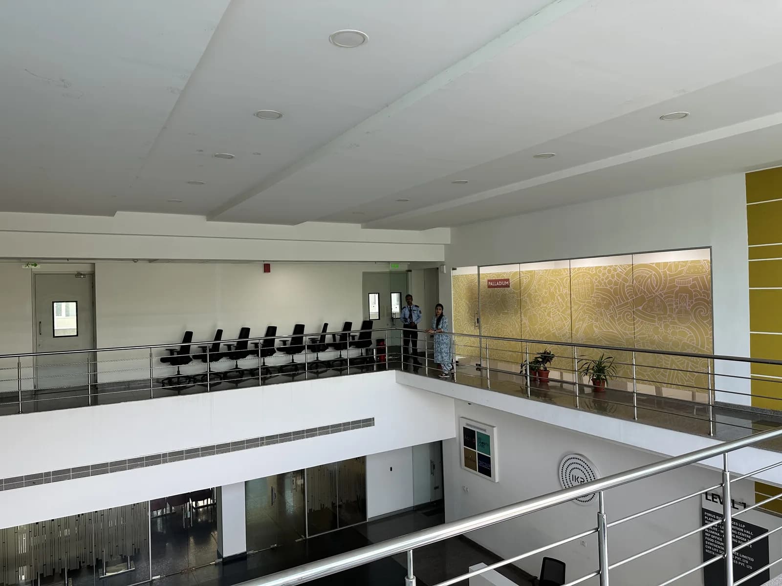 A mezzanine walkway above the atrium, chairs set along its glass balustrade