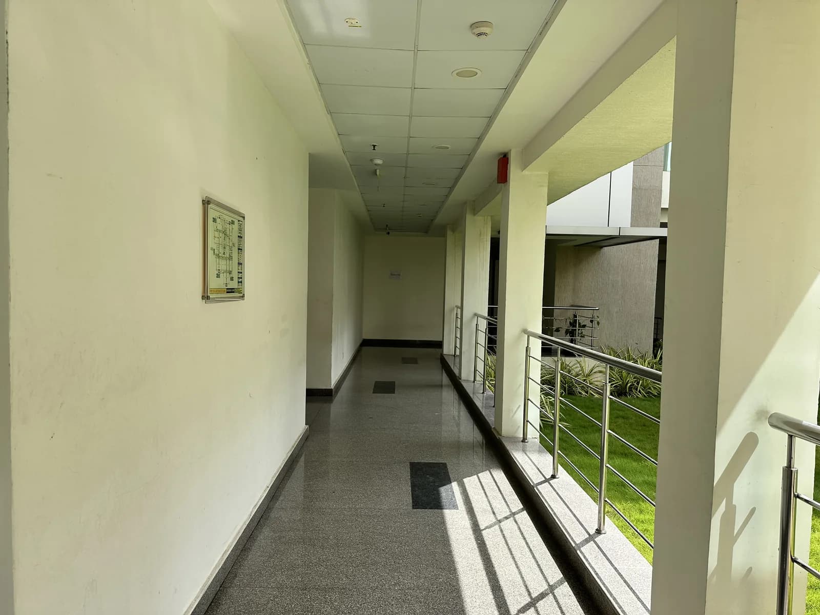 A plain corridor lit from one side, a framed print on the end wall