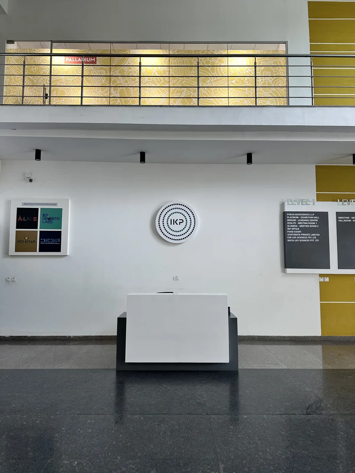 A double-height reception hall with a wall clock, notice boards and a yellow panel