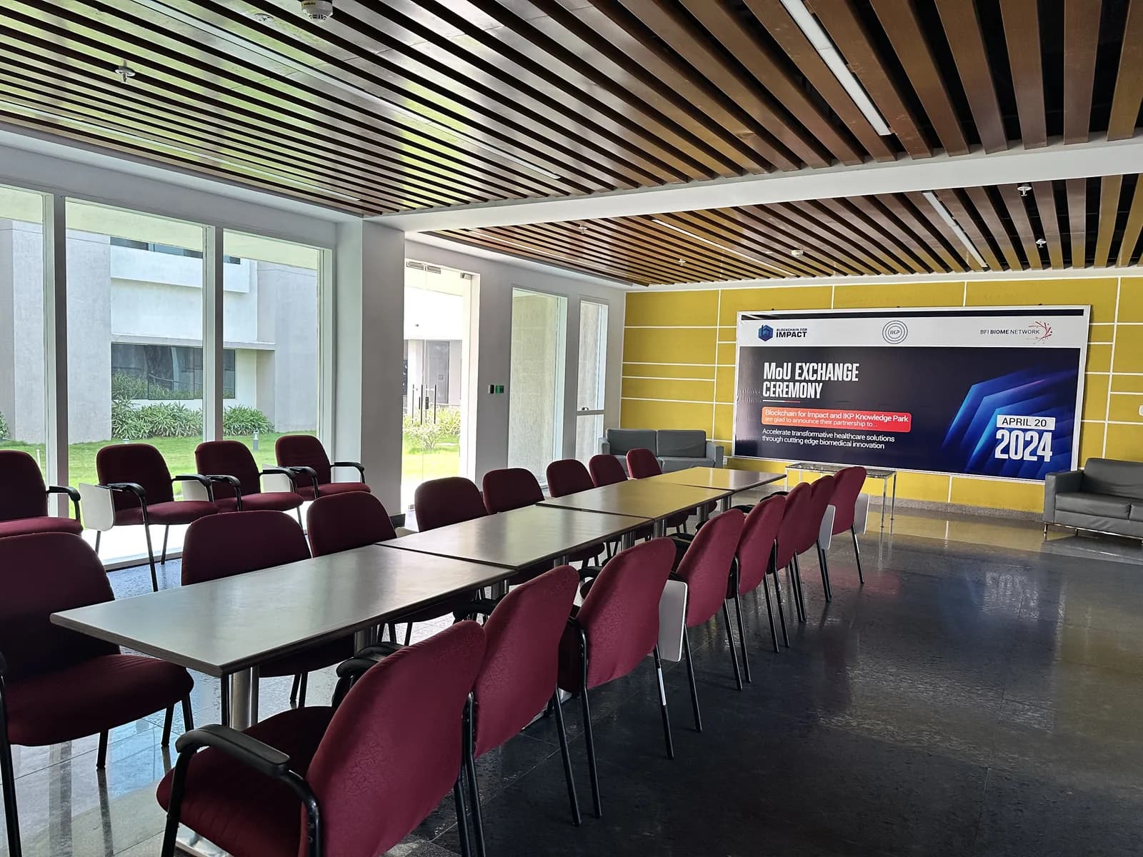 A learning hall with a screen and rows of tables under a battened timber ceiling