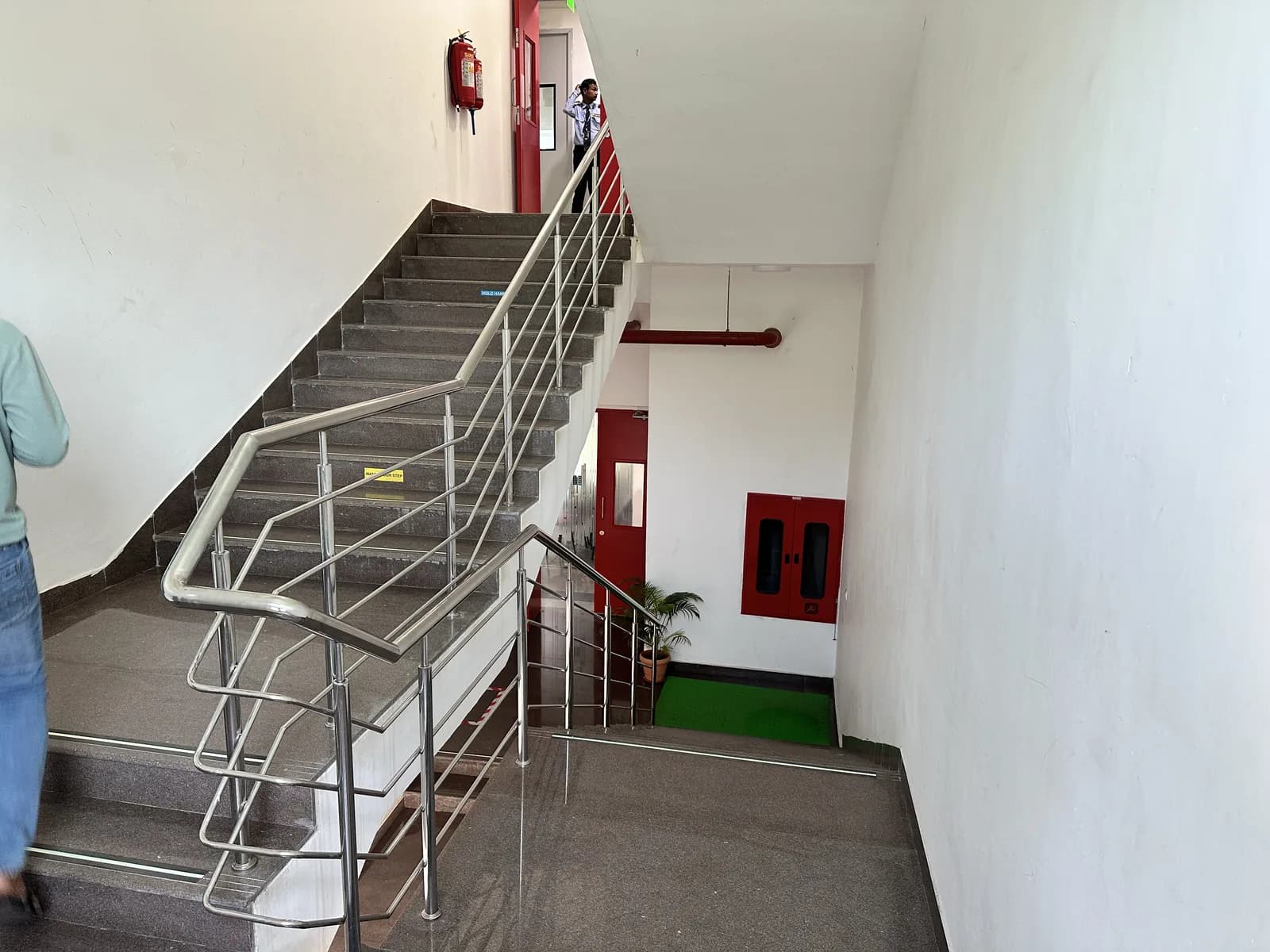 A stair rising against a white wall with a steel balustrade