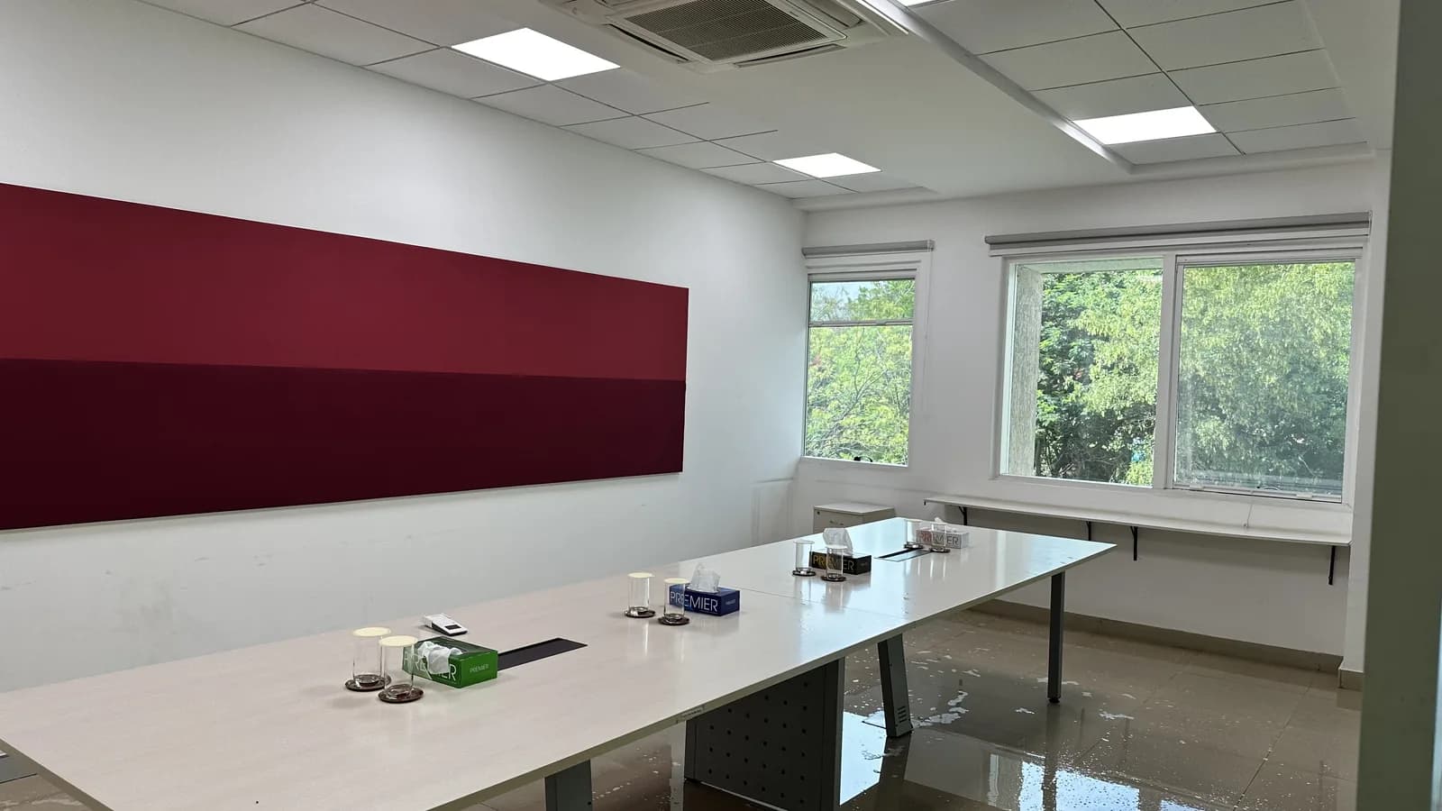 A meeting room with a long table and a deep red wall panel