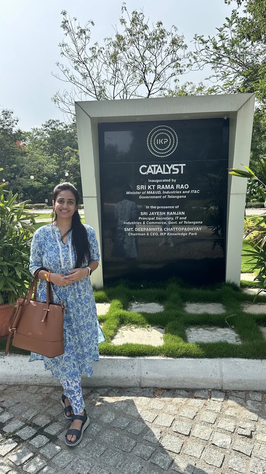 A visitor standing beside the Catalyst building's dedication plaque, planting either side