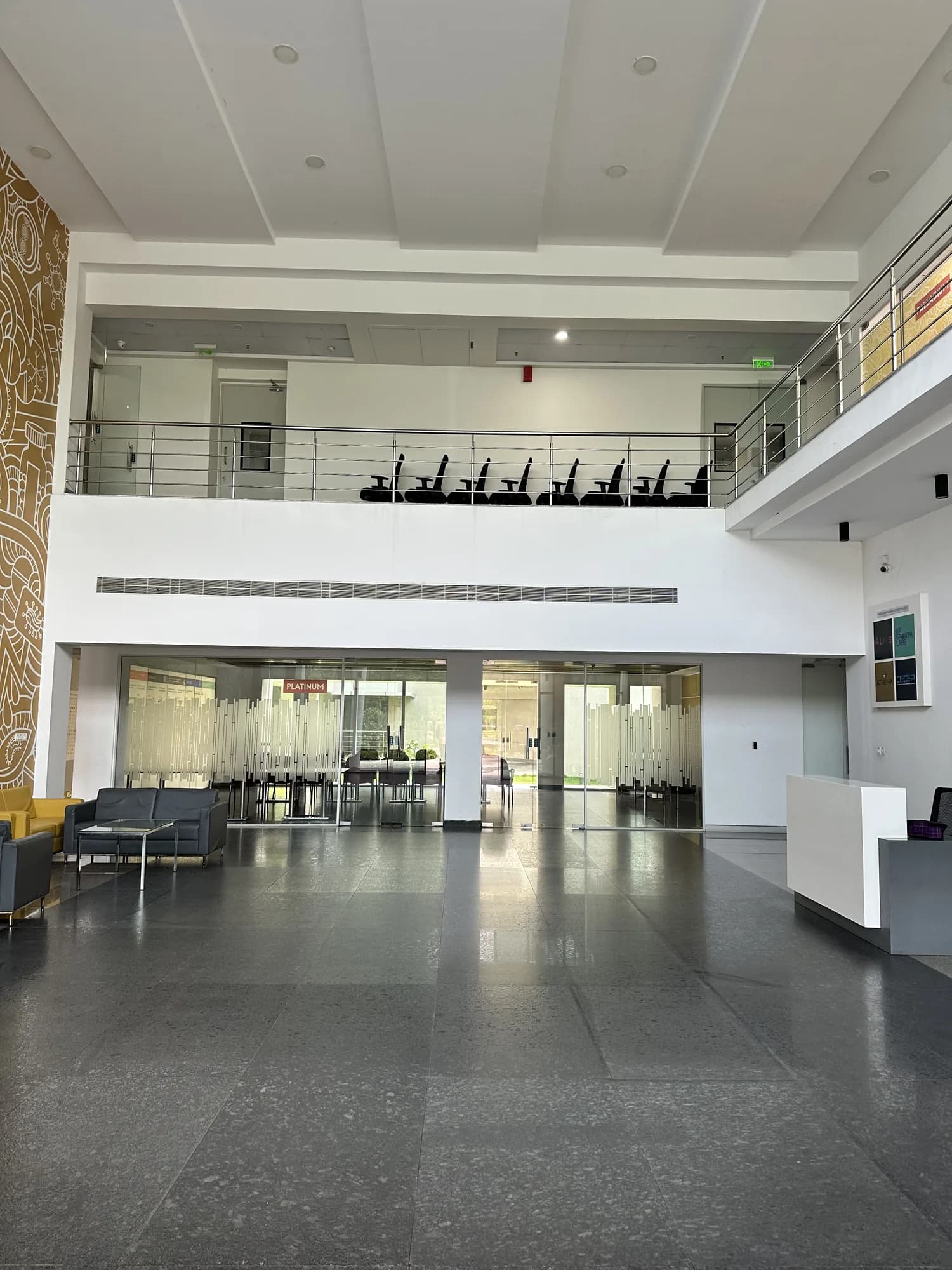 An office atrium below a mezzanine walkway, seating along the glazed front