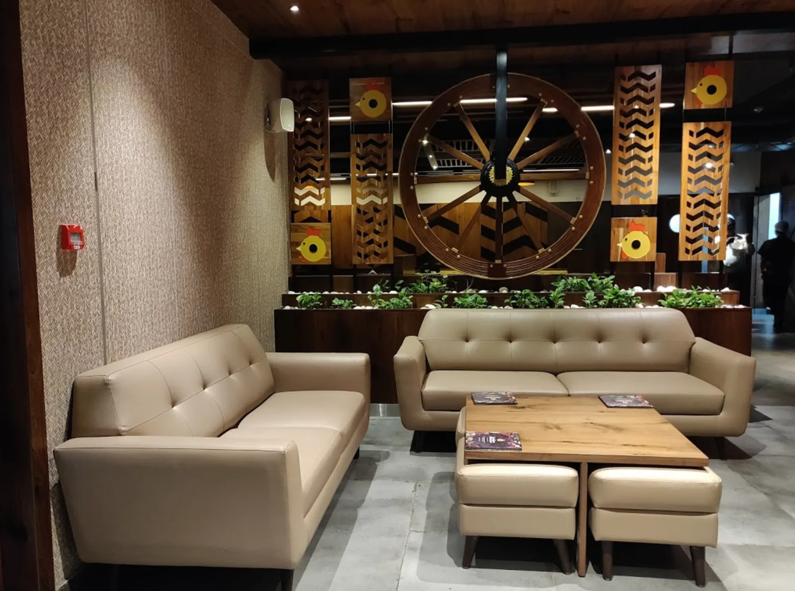 Cream lounge seating below a mounted cart wheel and a planted trough