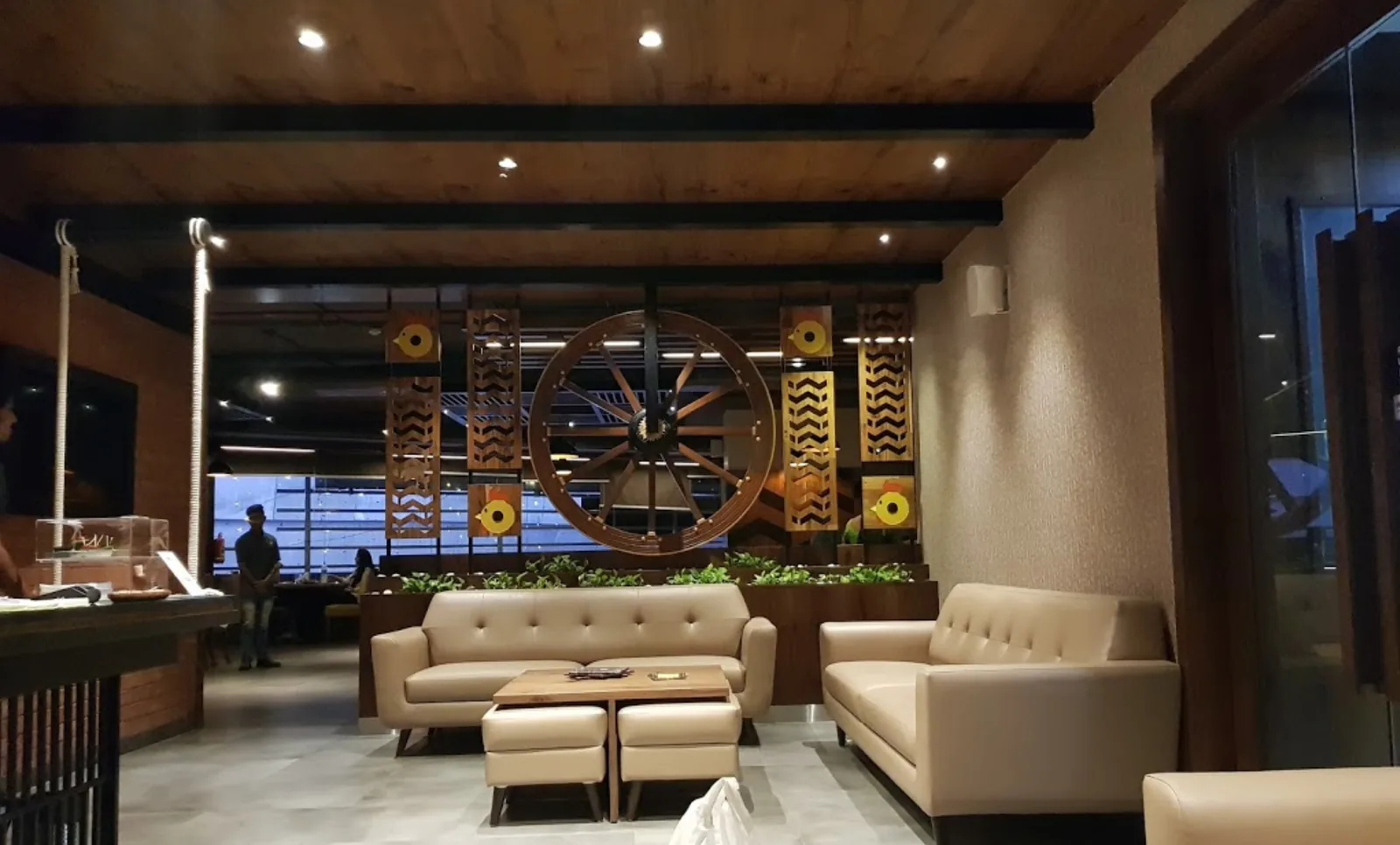 A cart wheel and patterned timber panels above cream sofas and low tables