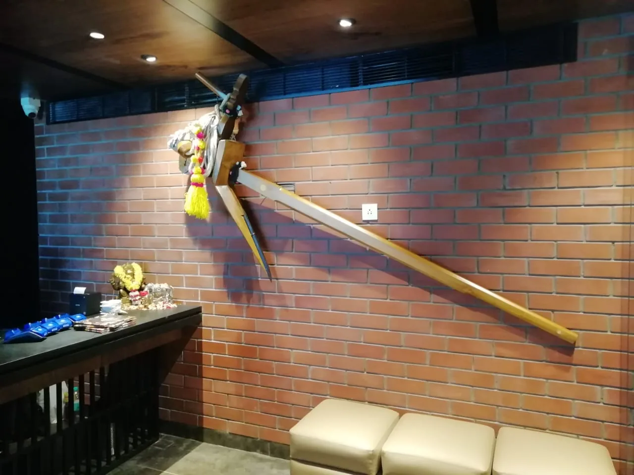 An exposed brick wall hung with a ceremonial spear, above bench seating
