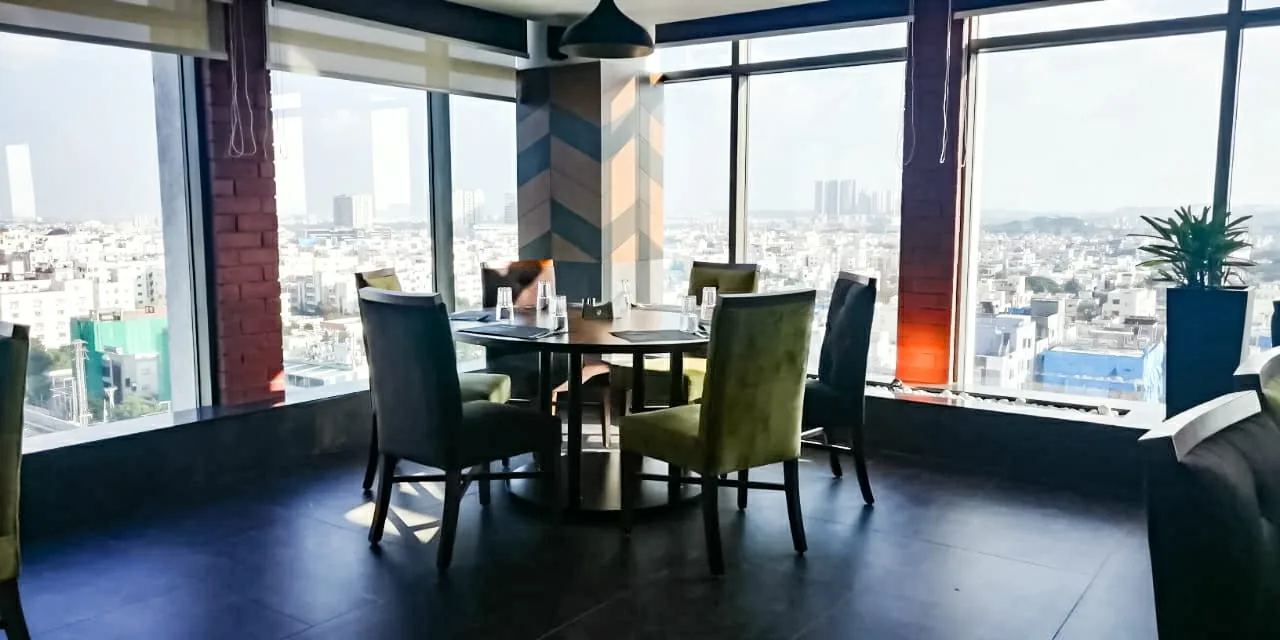 Window seating below chevron panelling, the city visible through full-height glazing