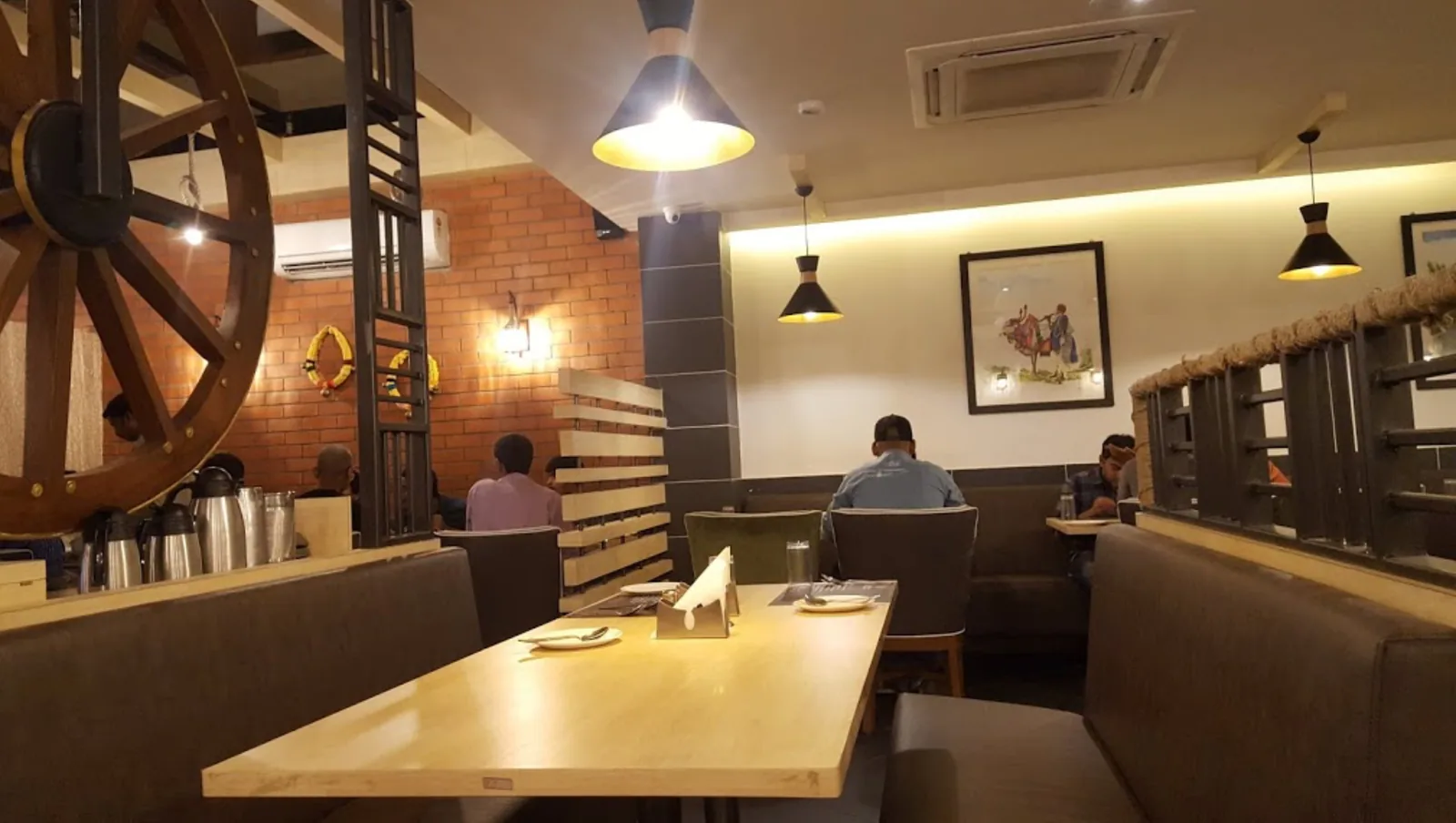 A dining room with a cart wheel mounted on exposed brick above the banquettes
