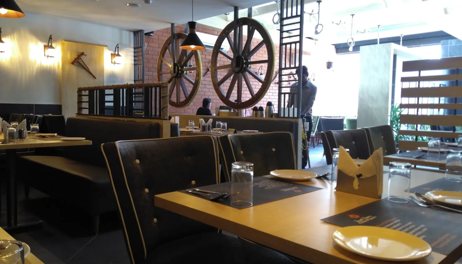 Banquette seating laid for service, a cart wheel on the wall beyond