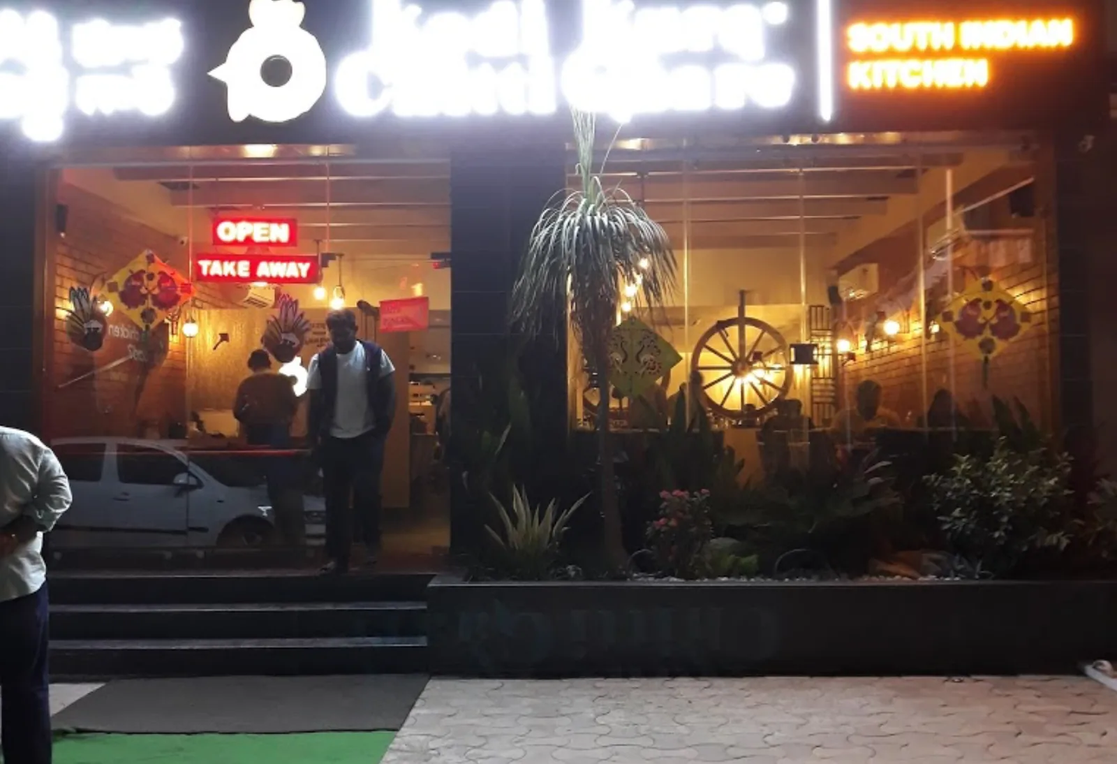 The shopfront by day, planting and a cart wheel flanking the entrance
