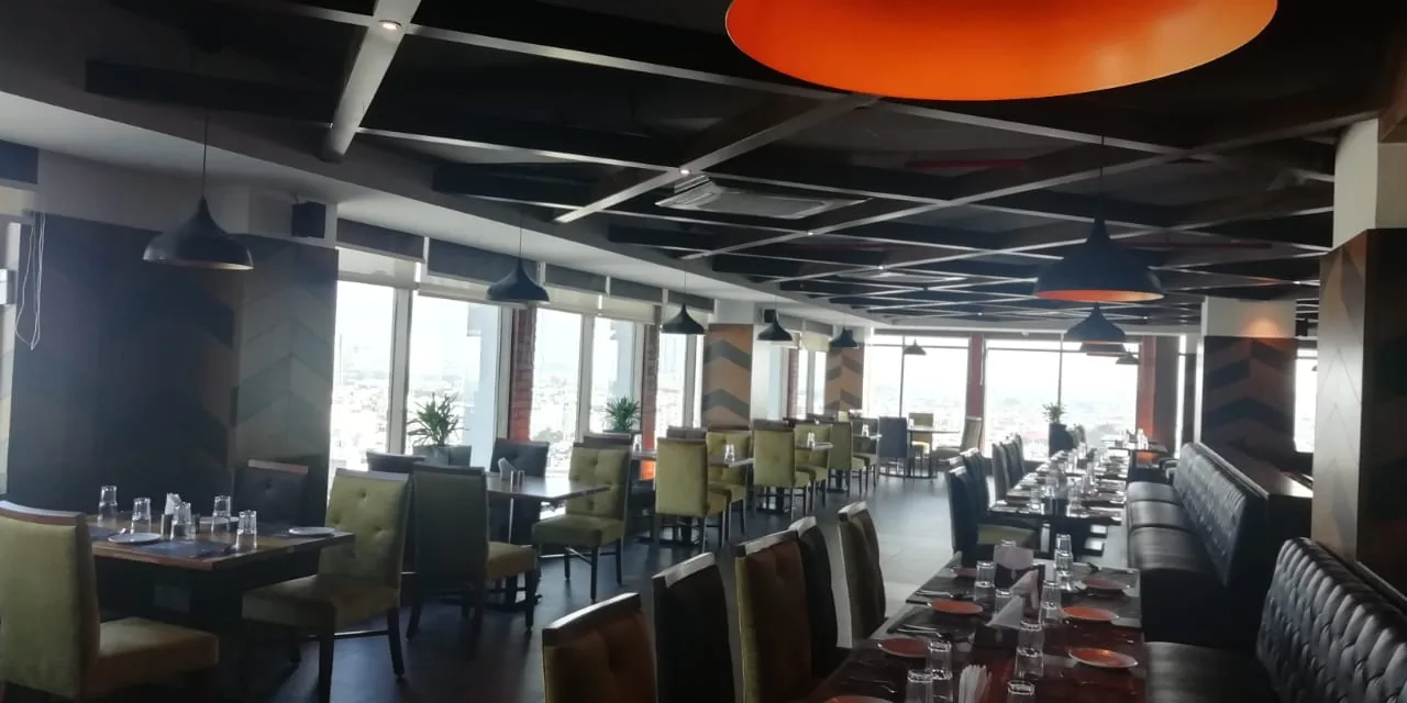 An upper dining room laid for service beneath a lit ceiling disc