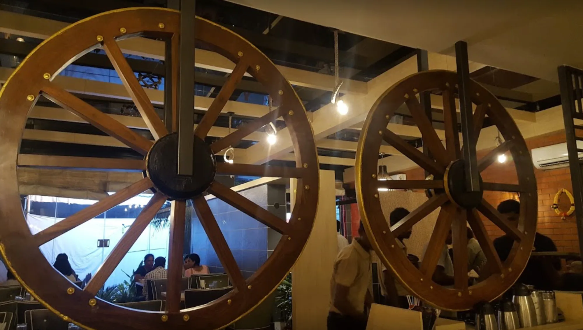 Two large timber cart wheels mounted on the wall of a restaurant dining room