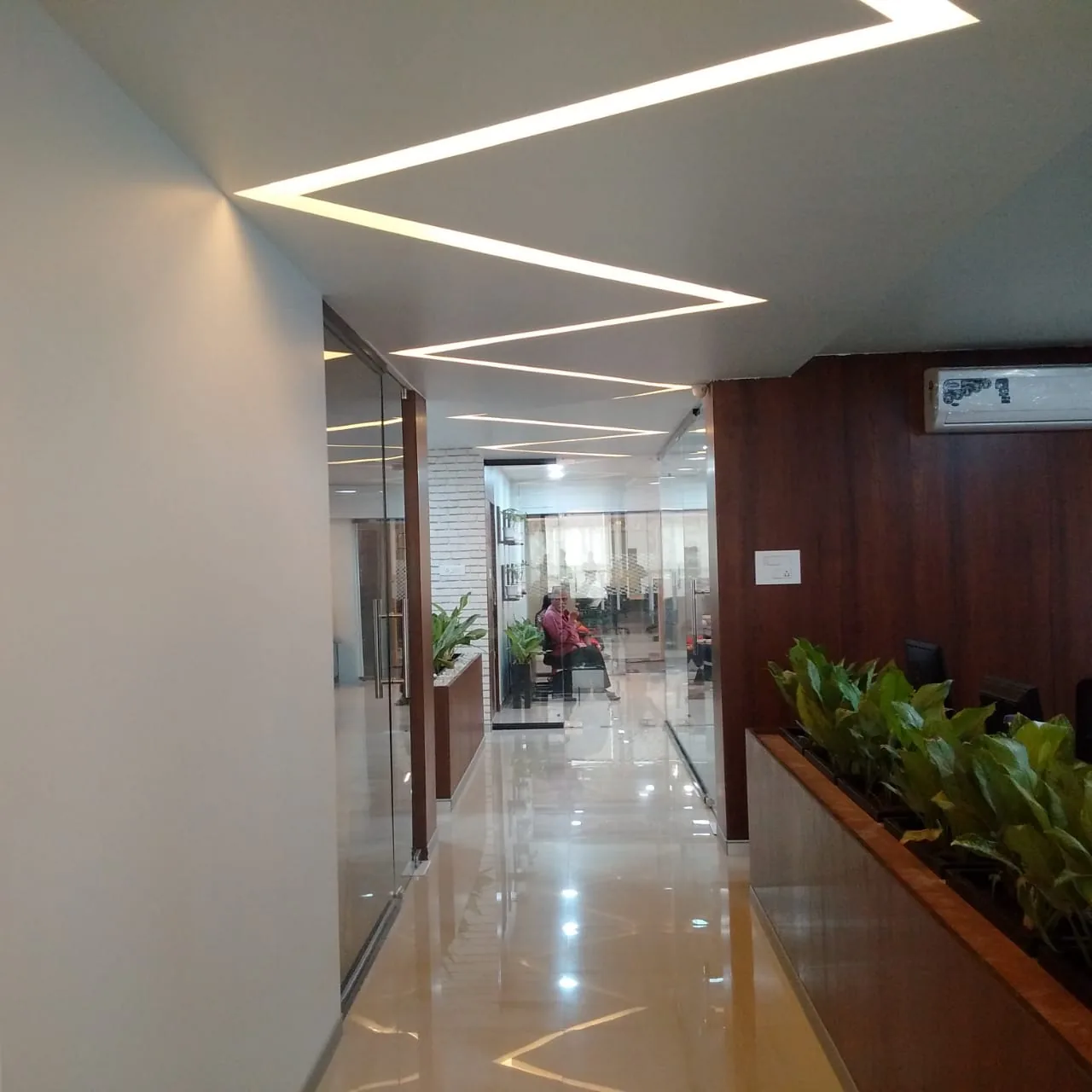 A corridor of glazed office cabins running beside a long planted timber trough