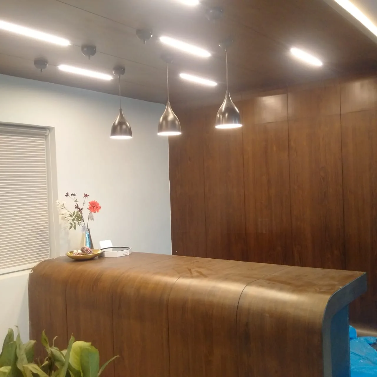 A curved timber desk beneath cone pendants against a panelled wall
