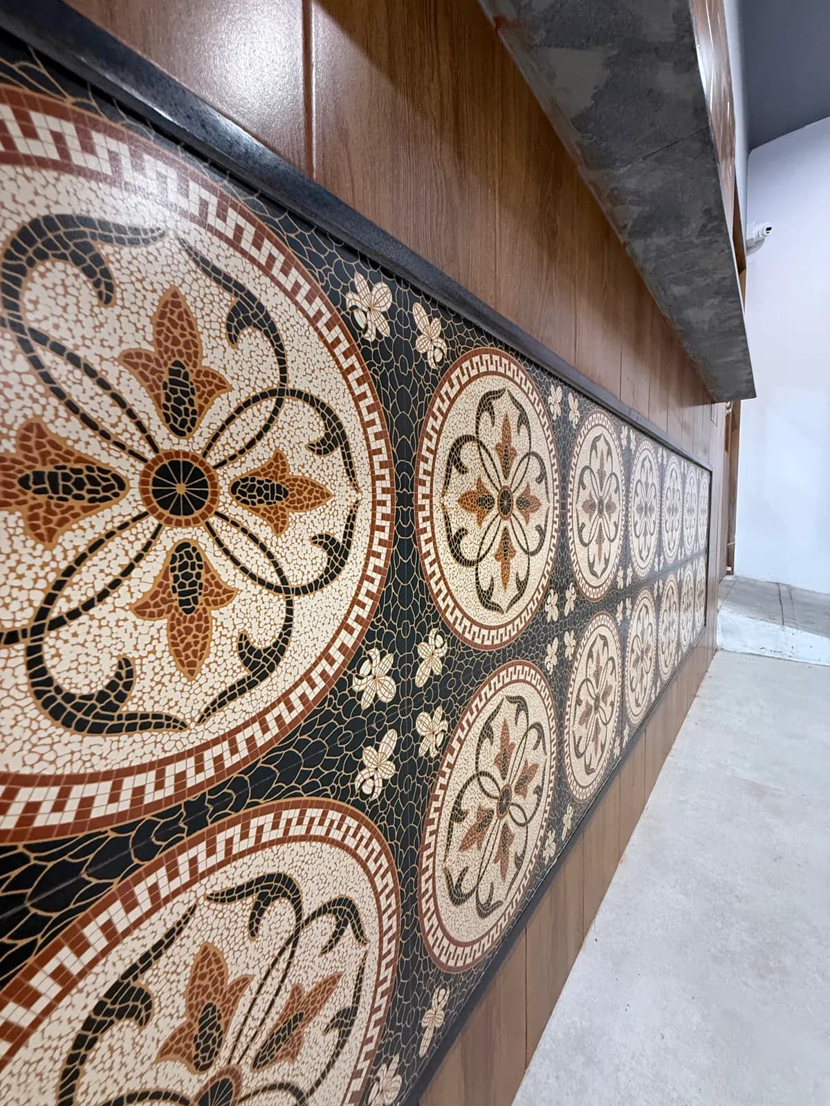 An inlaid mosaic floor panel in terracotta and cream, set into a timber floor