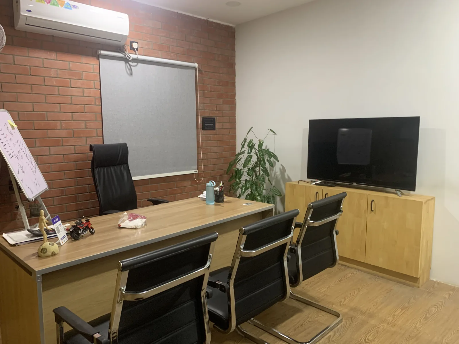 A meeting room with a long timber table and cantilever chairs below a wall-mounted screen