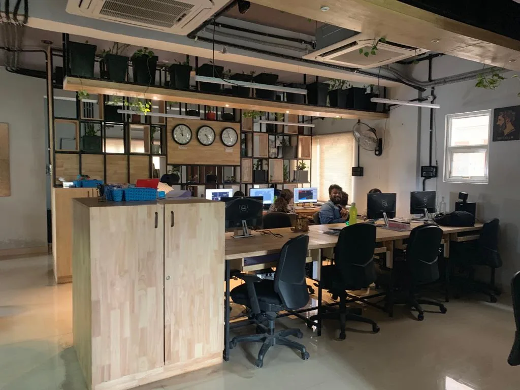 An open studio with rows of desks seen beyond a shelving screen