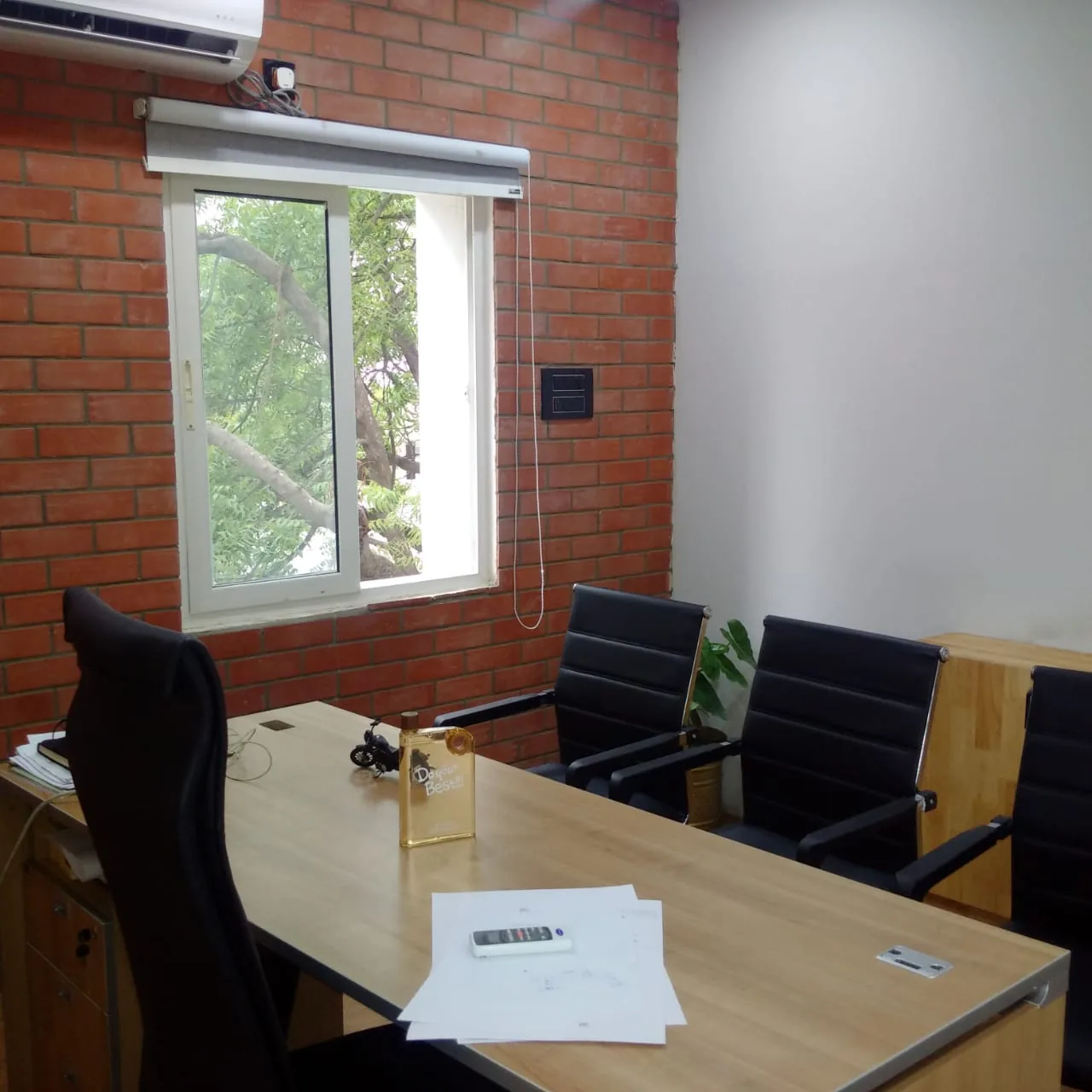 A meeting table beside a brick wall and a window onto trees