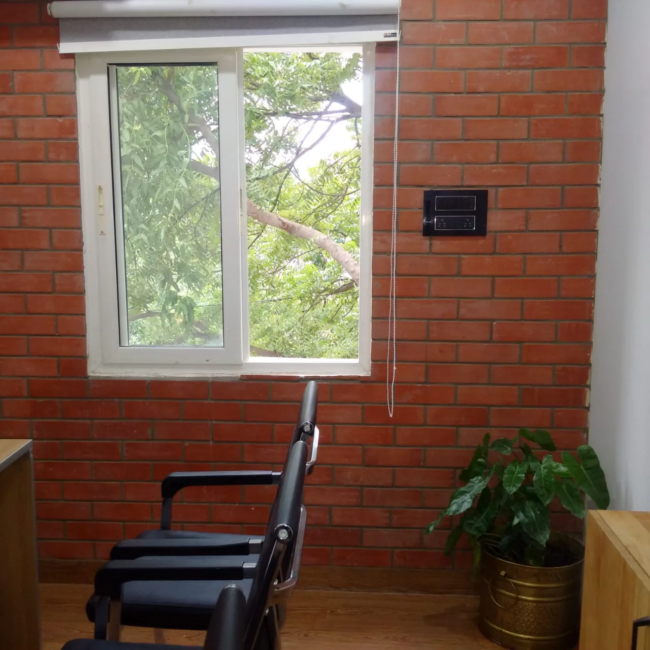 A window bay in exposed brick with a chair and a potted plant