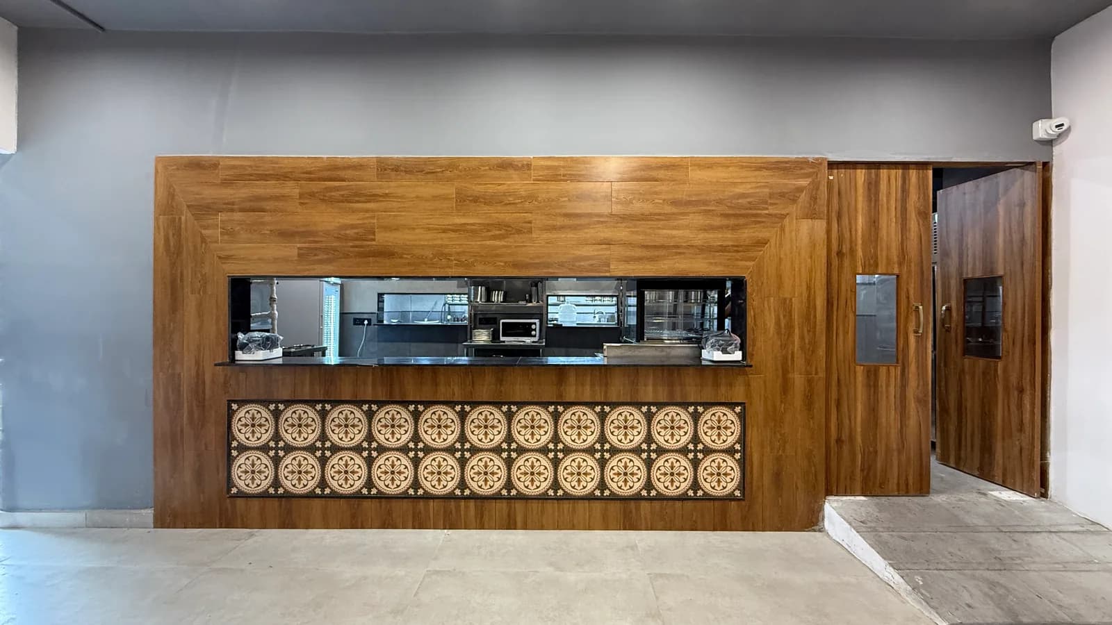 A long service counter clad in timber above a band of patterned cement tile