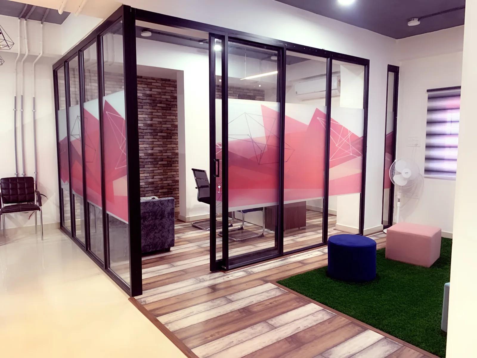 Black steel-framed glazed meeting cabins standing on a timber floor