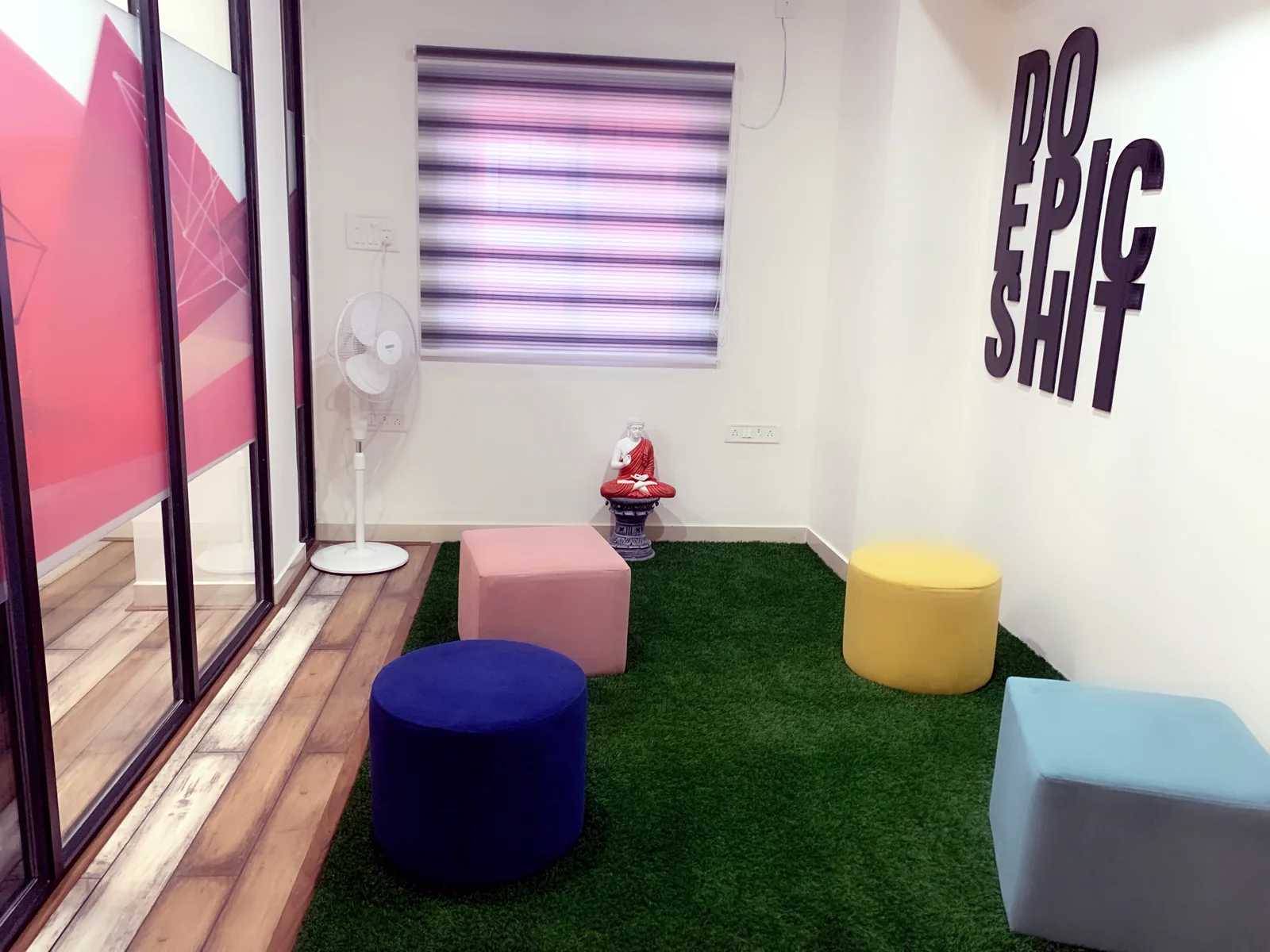 A breakout corner with an artificial lawn floor, coloured stools and a lettered wall