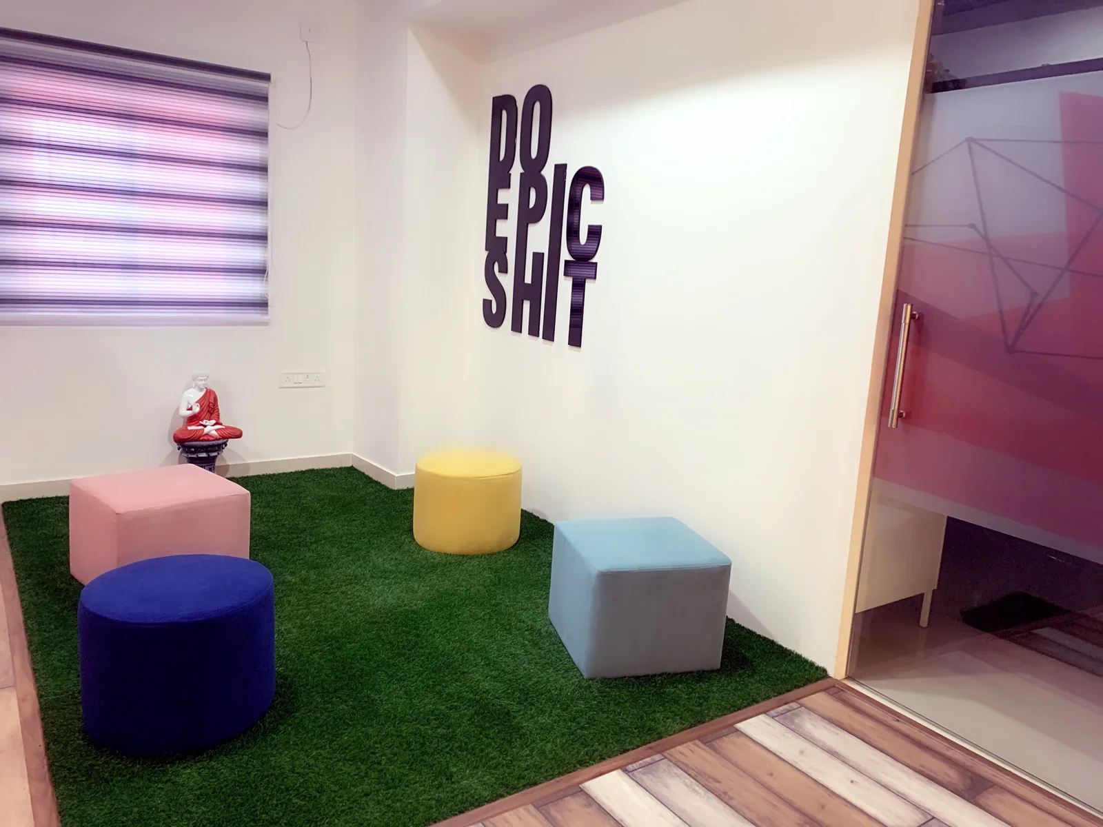 A breakout corner with soft stools beneath a bold wall slogan